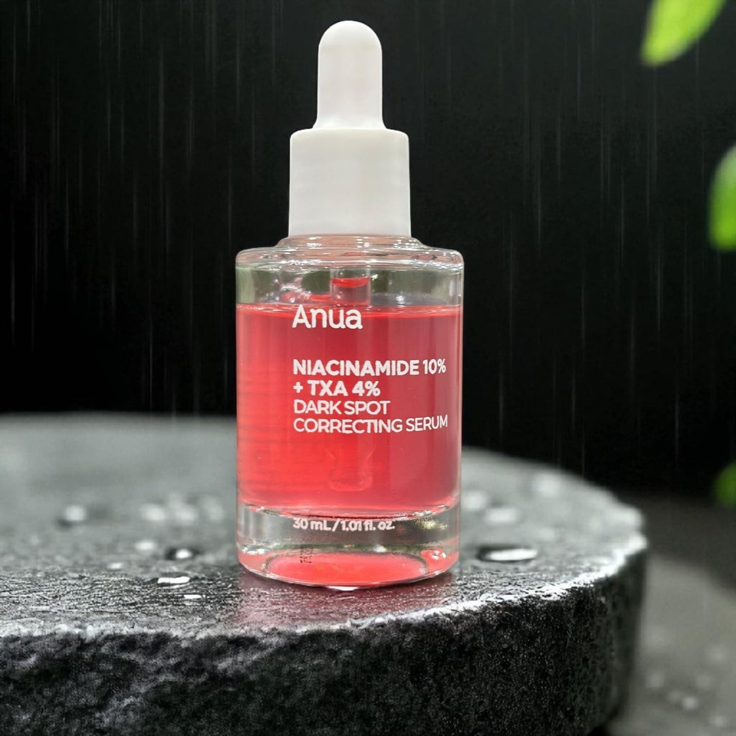 Anua dark spot correcting serum bottle on a dark surface with water droplets.