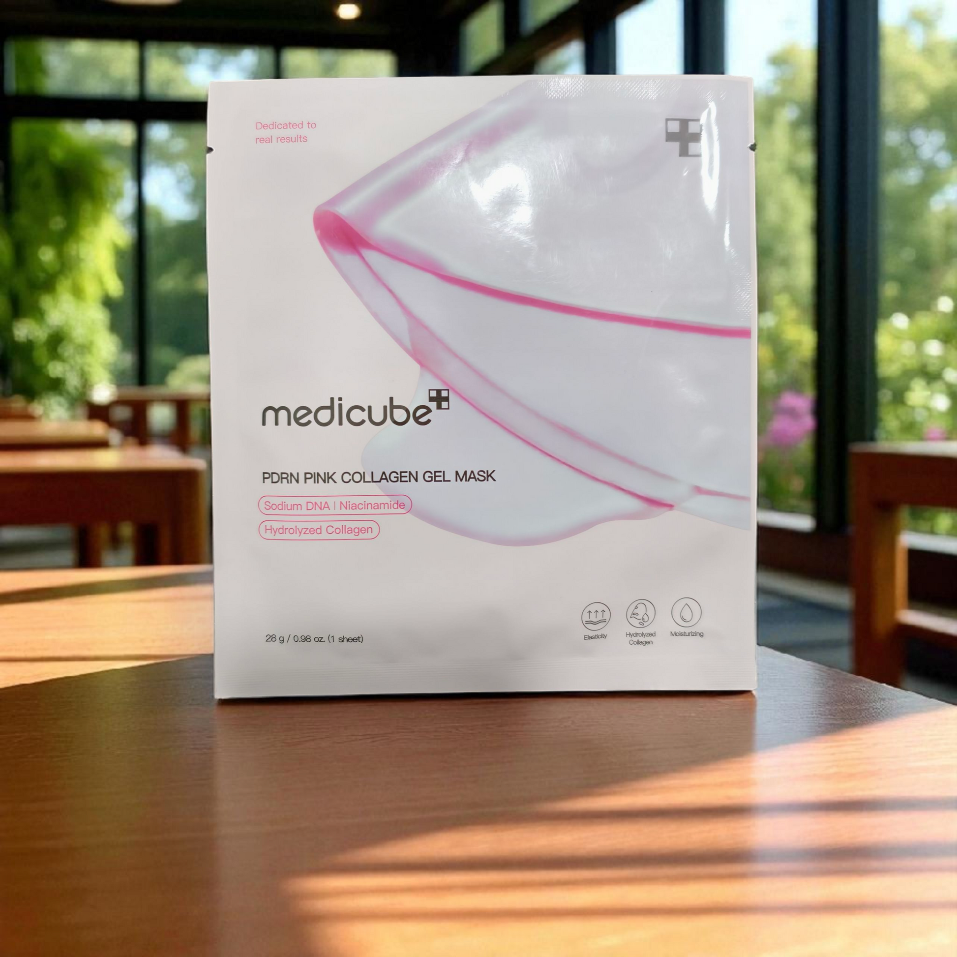 Box of Medicube pink collagen gel mask on a wooden table with a blurred outdoor background